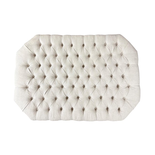 A substantial custom storage coffee table/ottoman featuring deep diamond button tufting in a neutral ivory-beige woven...