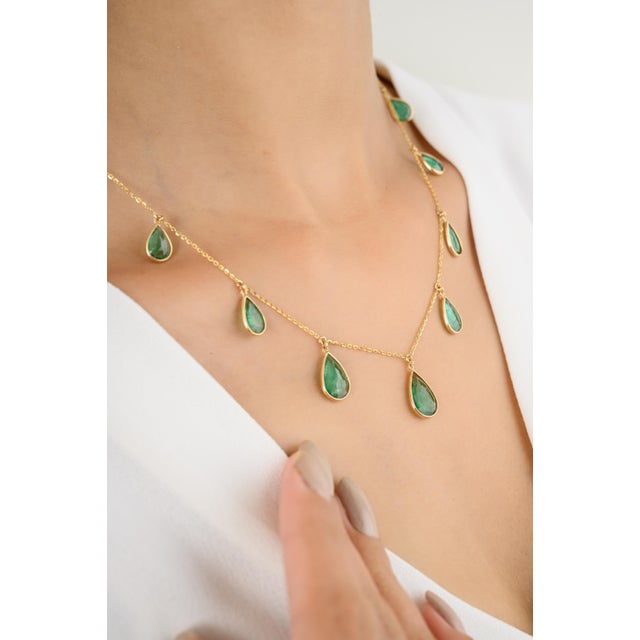 This exquisite necklace features a beautiful teardrop-shaped emerald that appears to float effortlessly on an 18k yellow...