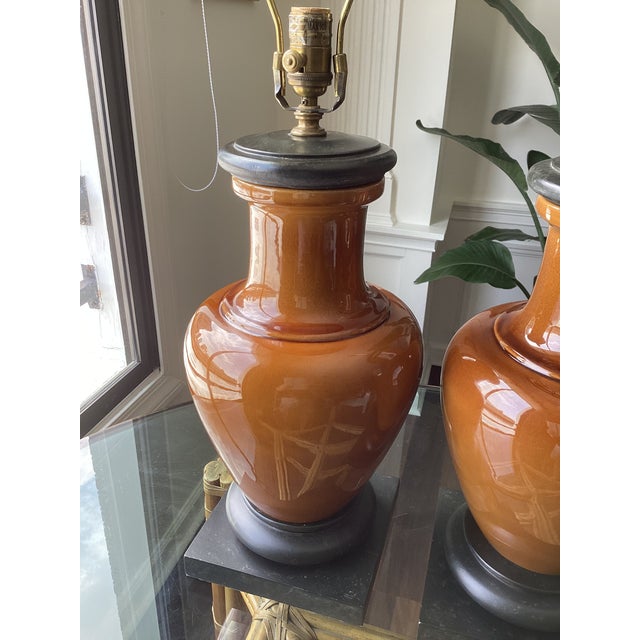 A sophisticated pair of Visual Comfort ceramic table lamps featuring richly glazed caramel-hued urn-form bodies accented...