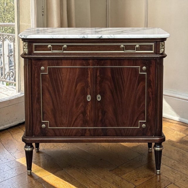 French Mahogany Louis XVI Style Two-Door Buffet with Carrara Marble Top draws on the elegant restraint of neoclassical and...
