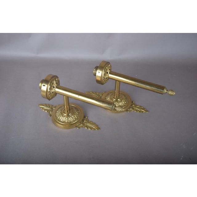 Pair of solid brass wall sconces with straight torch-form stems, ornate round backplates and pineapple finials. Fluted...