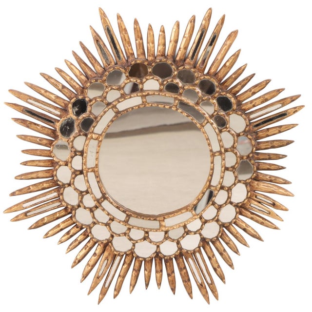 The sunburst style frame having four stepped layers of smaller mirrors surrounding a larger, central round looking glass....