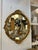 Vintage oval wall mirror with carved solid wood frame in gold leaf finish. Frame features raised scroll and foliate...