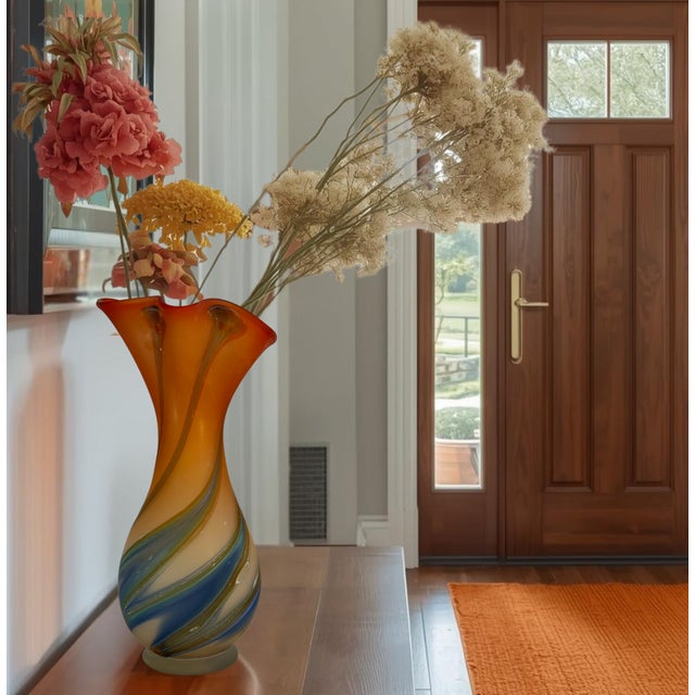 This 14‑inch tall by 6‑inch wide hand‑blown art glass vase by Essie Zareh of Azerbaijan reflects the expressive, organic...