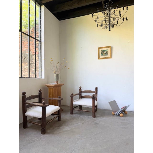 Pair of dark oak armchairs from the 1950s attributed to charles dudouyt. their compact design, with low seats, is...