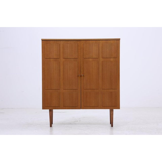 Vintage linen cupboard from the 1960s. The framed doors and warm wood finish give the cupboard a serene mid-century modern...