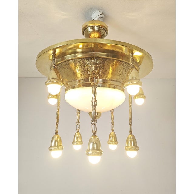 Art Nouveau chandelier in polished brass with an opal glass centerpiece and bronze lion heads. It has been rewired at some...