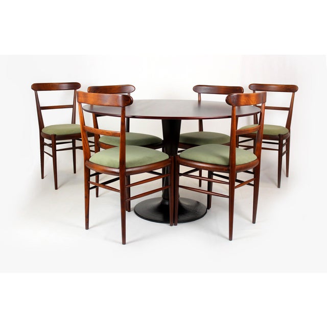 A cohesive mid-century modern dining set consisting of six dining chairs and a round dining table, produced in...