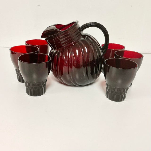 This is a gorgeous Pitcher and Glassware Set from the Early 20th Century. It features pressed glass in a deep shade of...