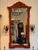 A red chinoiserie mirror, the shaped pagoda crest painted with two figures beside a fence before a pagoda and willow,...