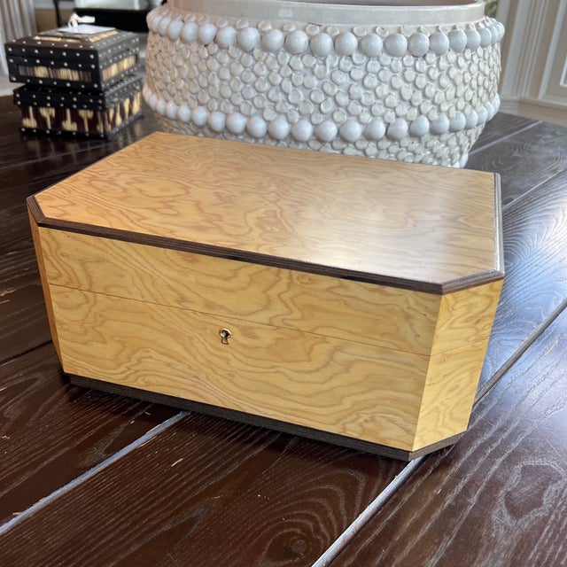 This vintage jewelry box is crafted from light-colored maple wood featuring a distinct canted top design and dark trim edging