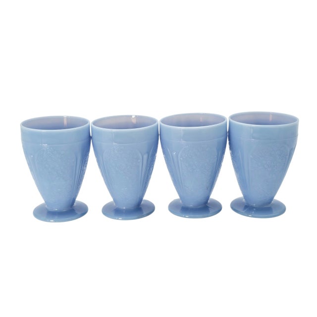 This set of four footed juice tumblers was produced by Jeanette Glass in the Cherry Blossom pattern, a Depression-era...