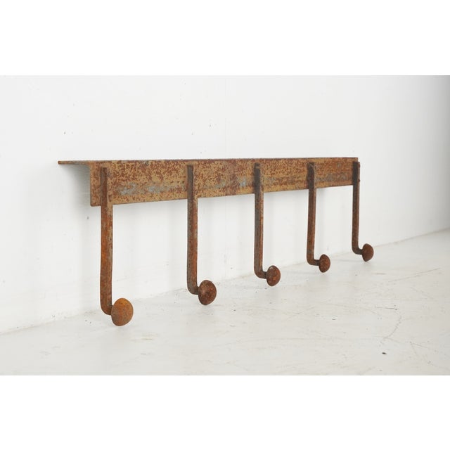 Industrial style wall hook rail with five peg hooks. It is made of wrought iron with a distressed rusted finish. It has a...