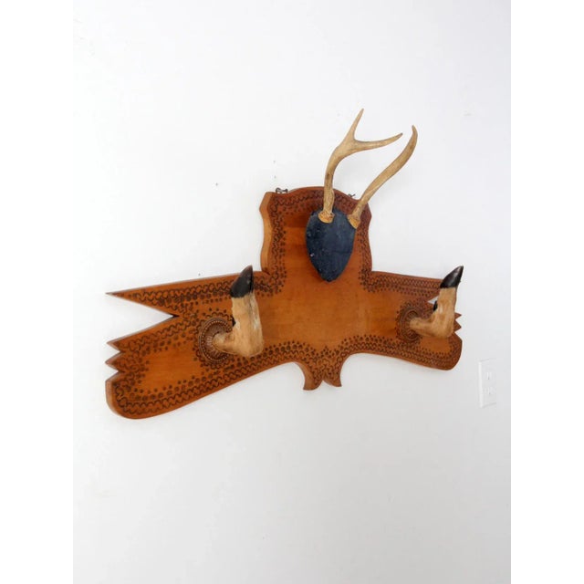This vintage 1957 wall-mounted deer antler display features a carved wooden plaque with tooled scalloped edging. The...
