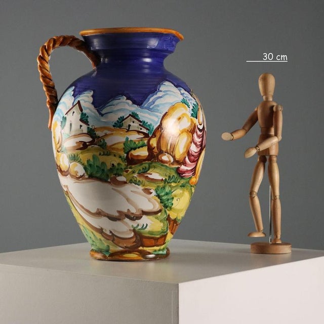 Taccini-manufactured majolica amphora, decorated all over with a mythological scene. The handle is shaped like intertwined...