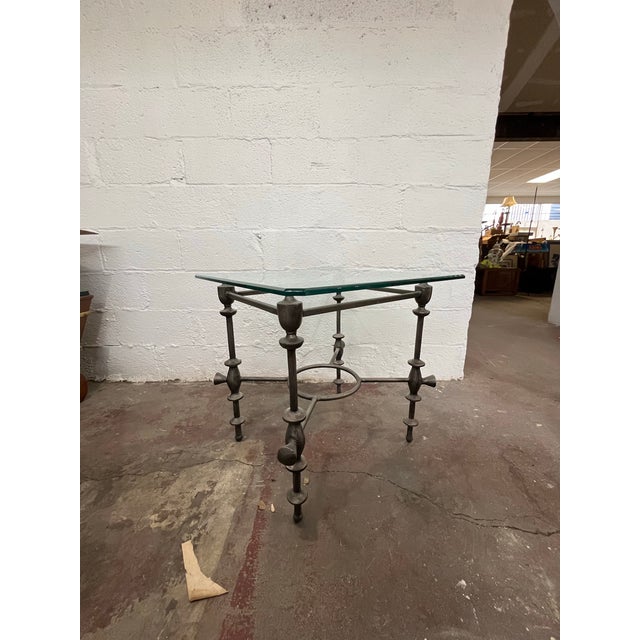 A striking mid-century brutalist side table featuring forged metal designed base with sculptural baluster-form legs and an...