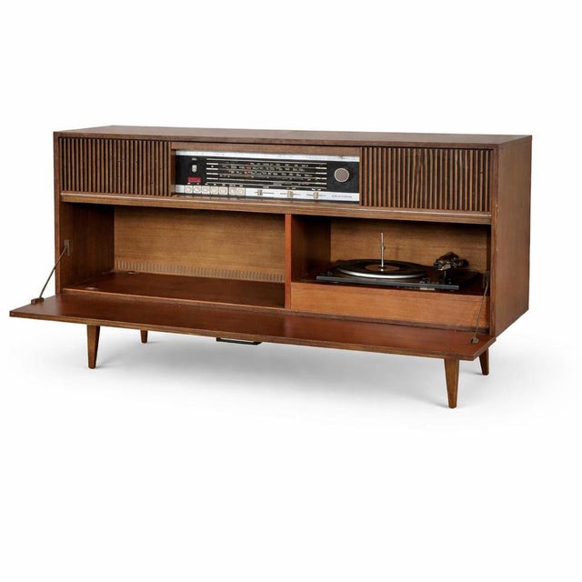 A sleek and beautifully proportioned mid-century Grundig radiogram, combining rich walnut-toned cabinetry with striking...