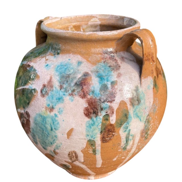 Vintage terracotta cachepot featuring a classic amphora form with twin handles and an expressive multicolor drip glaze...