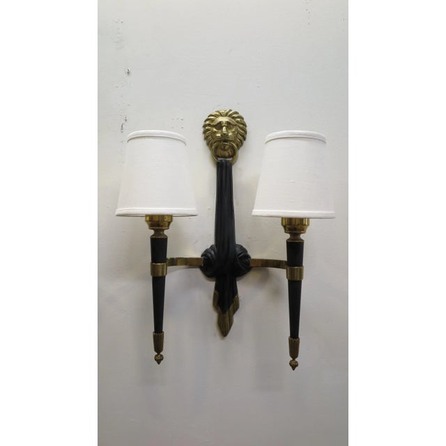 Pair of French midcentury sconces attributed to Maison Jansen. Elegant brass and bronze lion topped sconces with two...