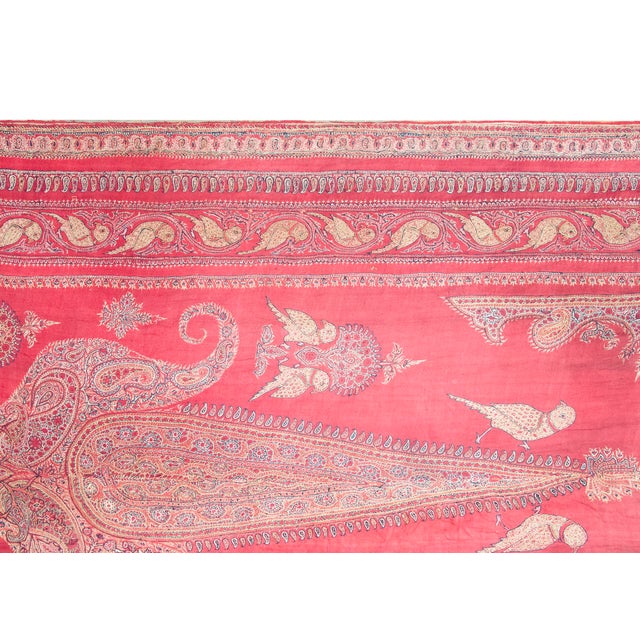 An exquisite antique Persian Kirman Suzani hand-woven silk textile featuring a vibrant red ground adorned with intricate...