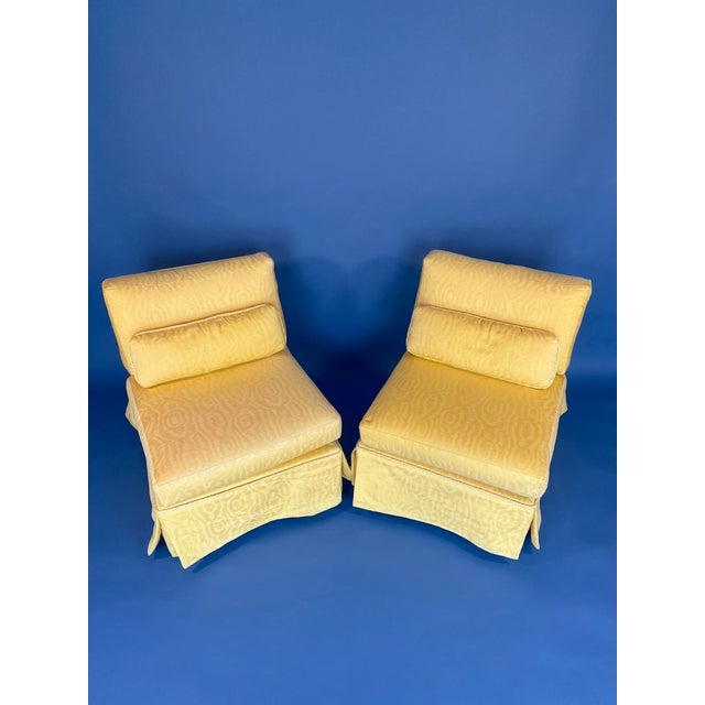 Pair of upholstered slipper chairs featuring a low-profile design, plush cushions, and skirted bases. The chairs are a bit...