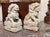 A lively pair of carved marble foo dogs, each seated on a decorated rectangular plinth. One rests a paw on a sphere, the...