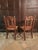 A charming pair of late 19th-century English pitch pine hall chairs, each with a beautifully shaped dished seat displaying...