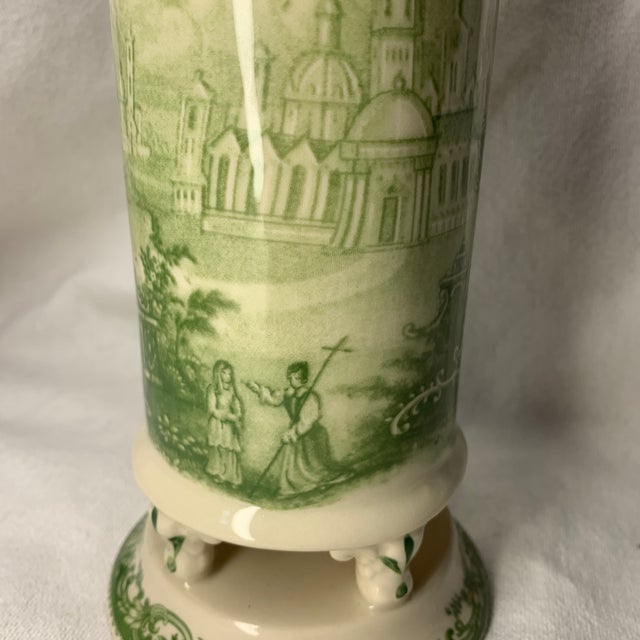This is a green toile transferware footed ceramic vase featuring classic pastoral and architectural vignettes.