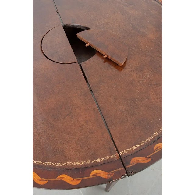 This Dutch game table/console is made of mahogany with impressive satinwood marquetry, circa 1795. When in demilune form...