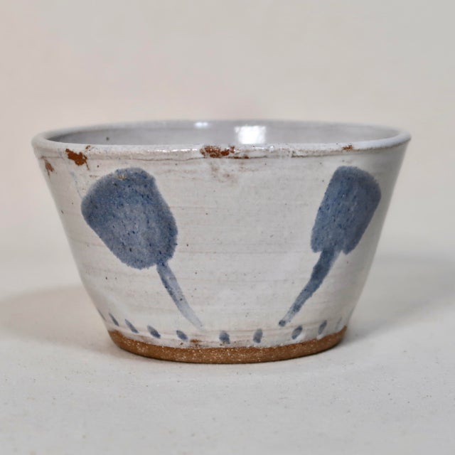 Handmade studio pottery bowl featuring a softly flared silhouette with hand-painted blue botanical brushstroke motifs...