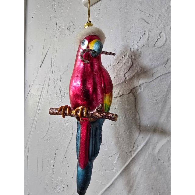 A vibrant and whimsical vintage mouth-blown glass Christmas ornament featuring a festive tropical scarlet macaw parrot....