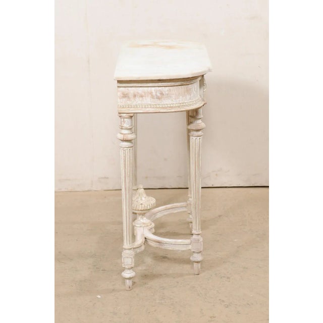 A French marble top console table, with carved urn finial accent at underside, from the mid 20th century. This vintage...