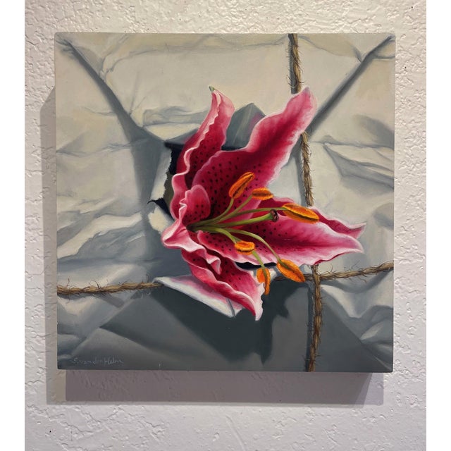 This oil painting features a vibrant stargazer lily emerging from a crumpled white package, creating a striking contrast...