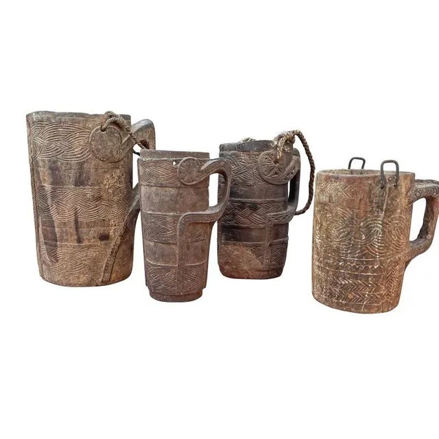 A group of beautifully carved wooden milk jugs. Vessels are covered with finely worked plaited band patterns and handles...