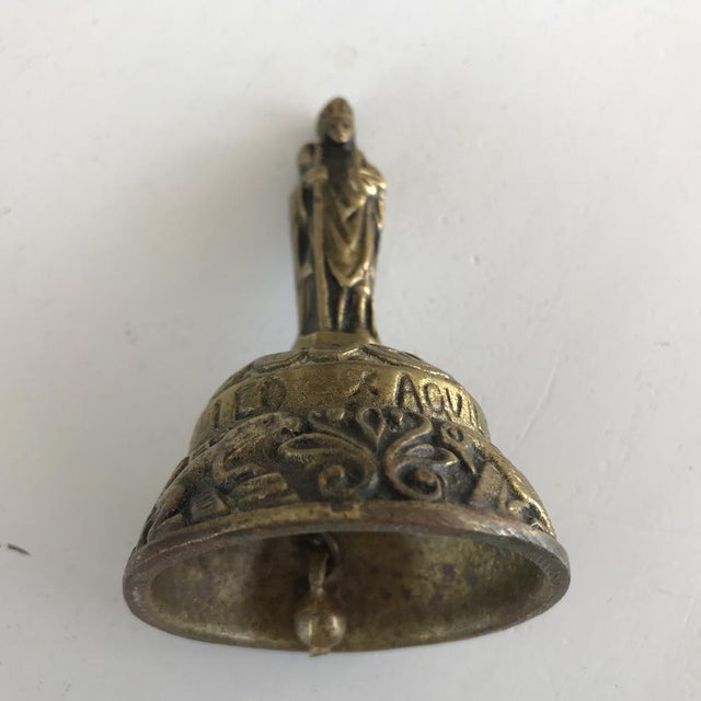 This is an antique 19th Century Victorian brass bell with a figure. It is signed by Leo x Aqvila Agnvs x Pelicani...