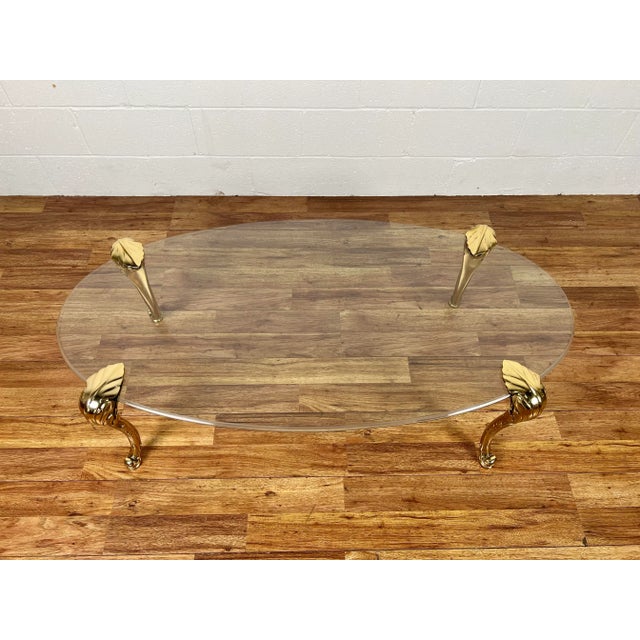 Stunning Maison Jansen style 1950s coffee table featuring thick, original glass top and heavy brass legs that are removable.