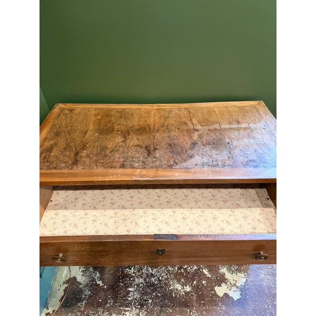This antique wooden dresser features three spacious drawers with brass knobs and decorative keyhole escutcheons. The warm...