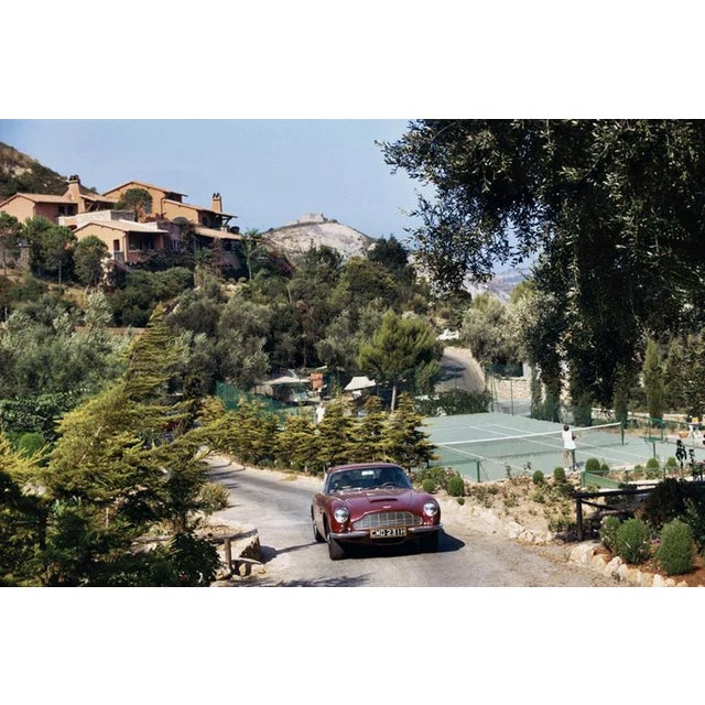 Il Pellicano Tennis 1973 by Slim Aarons Slim Aarons Limited Estate Edition An Aston Martin DB6 sports car driving past the...