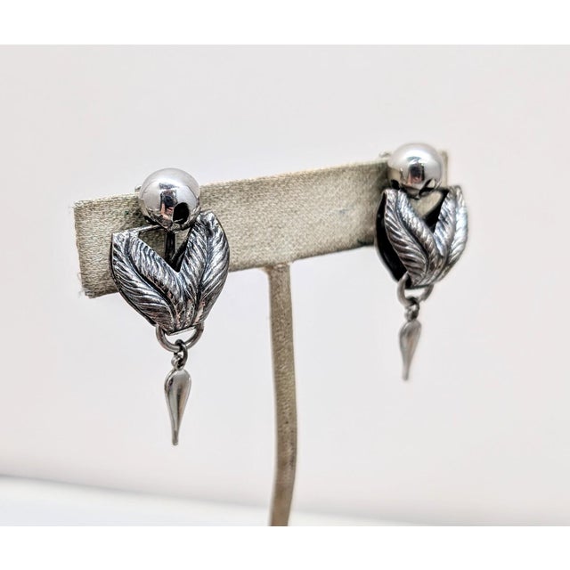 1950s rhodium plated spherical top with silvertone two textured laurel leaves hanging from it with a smooth rhodium plated...