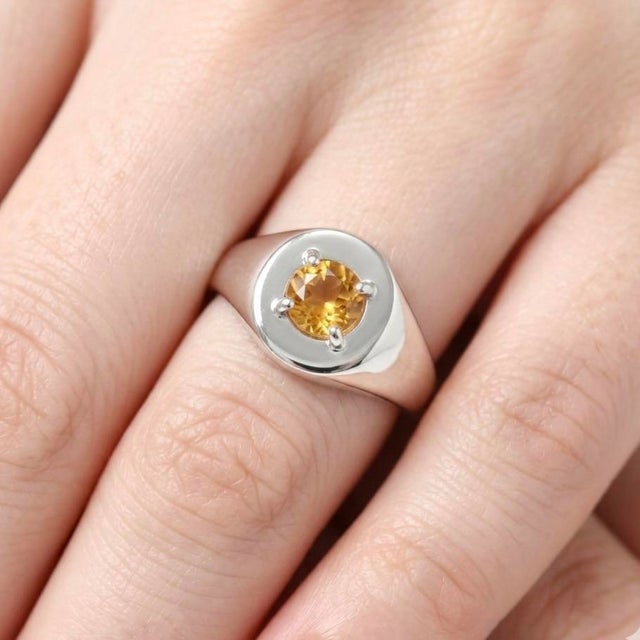 This bold and elegant ring features a radiant Citrine gemstone, admired for its warm golden hue and brilliant sparkle....