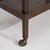 A mid-century modern bar cart mounted on casters for mobility. The frame is compact and functional, suitable for serving...