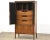 A mid century modern walnut and cane tall armoire dresser with brass knobs and revseable black panels. 33.75” wide. 18”...