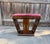 Elegant vintage vanity stool featuring a sculptural Art Deco silhouette with dramatic sloped sides and rich bookmatched...