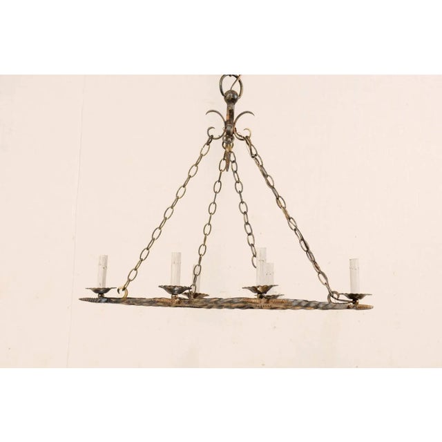 A French vintage six-light painted iron chandelier. This French mid-20th century iron chandelier has an overall...
