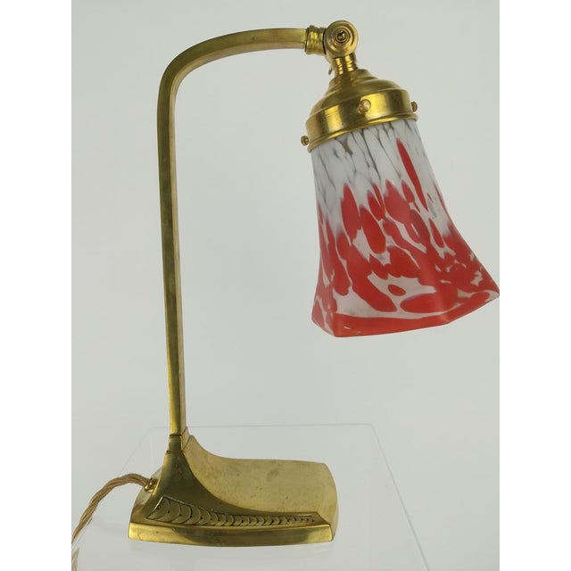 Art Nouveau brass table lamp with a mouth-blown pâte de verre shade. The light beam is adjustable. The lamp gives off a...