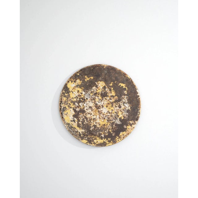 This wall mounted metal circle holds a pose resembling a clock face, its striking patina proving that it has certainly...