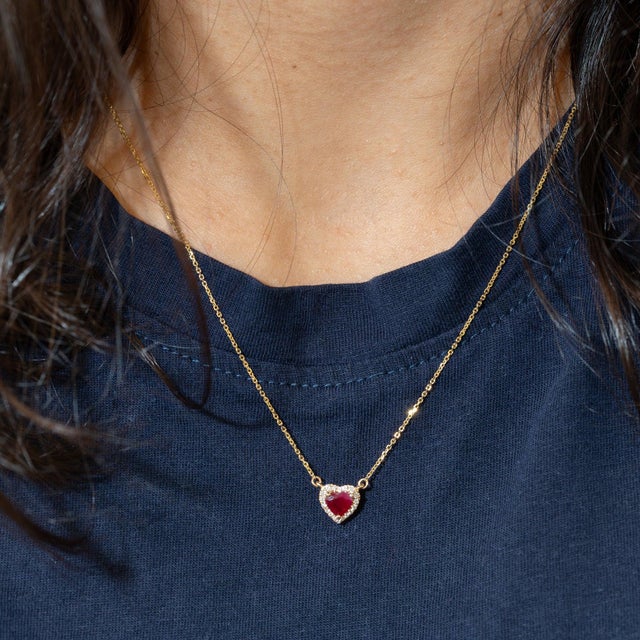 A 0.64-carat red mozambique ruby heart sits at the centre of this solid 14K yellow gold necklace, framed by eighteen...