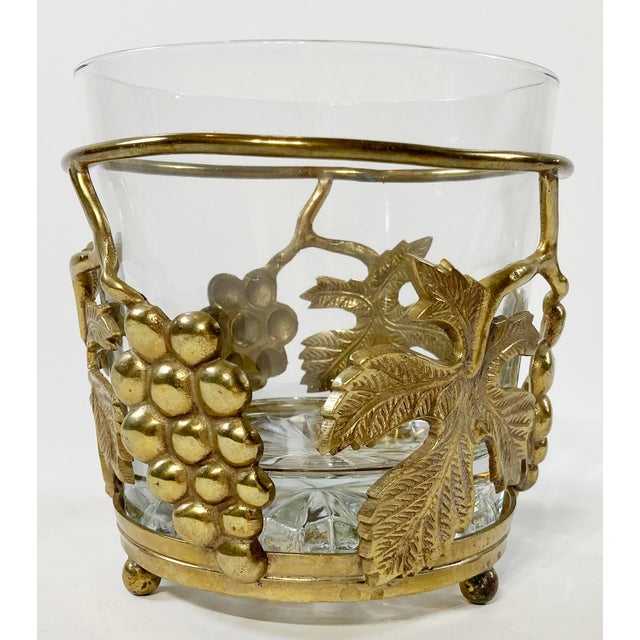 Unique vintage ice bucket with heavy cut glass insert held by a footed brass frame featuring detailed classic grape and...