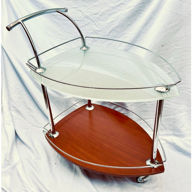 Elegant wheeling bar cart in a sleek Italian style with a tempered glass top, wood bottom and chrome fittings.