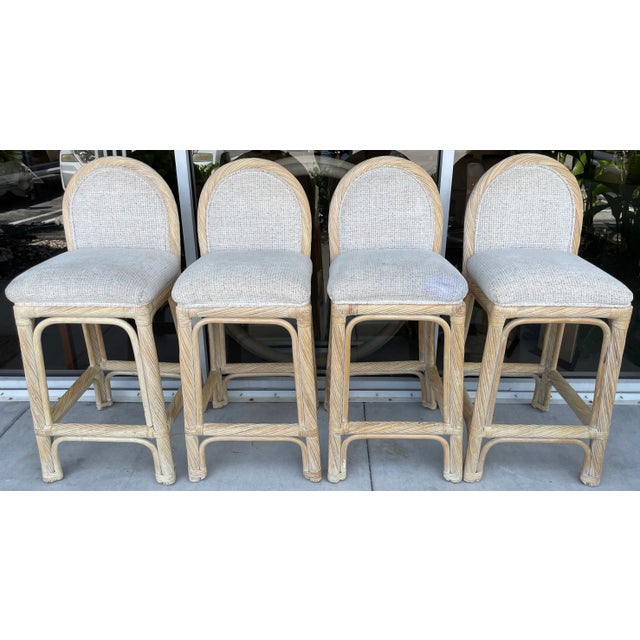Art Deco style set of 4 pencil reed bar stools from 80's. White washed finish, with upholstered back and seat. Sturdy and...